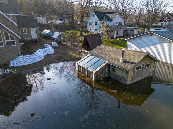 Spring flood water across yards and around houses, with sandbags along a garage