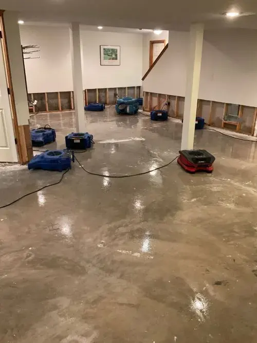Air movers drying a flooded basement after the lower drywall was cut out, basement flooding cleanup in Anoka