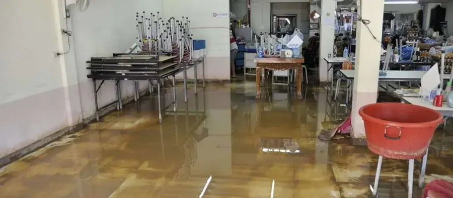Standing water across the floor of a commercial room with stacked tables, commercial water damage in Anoka